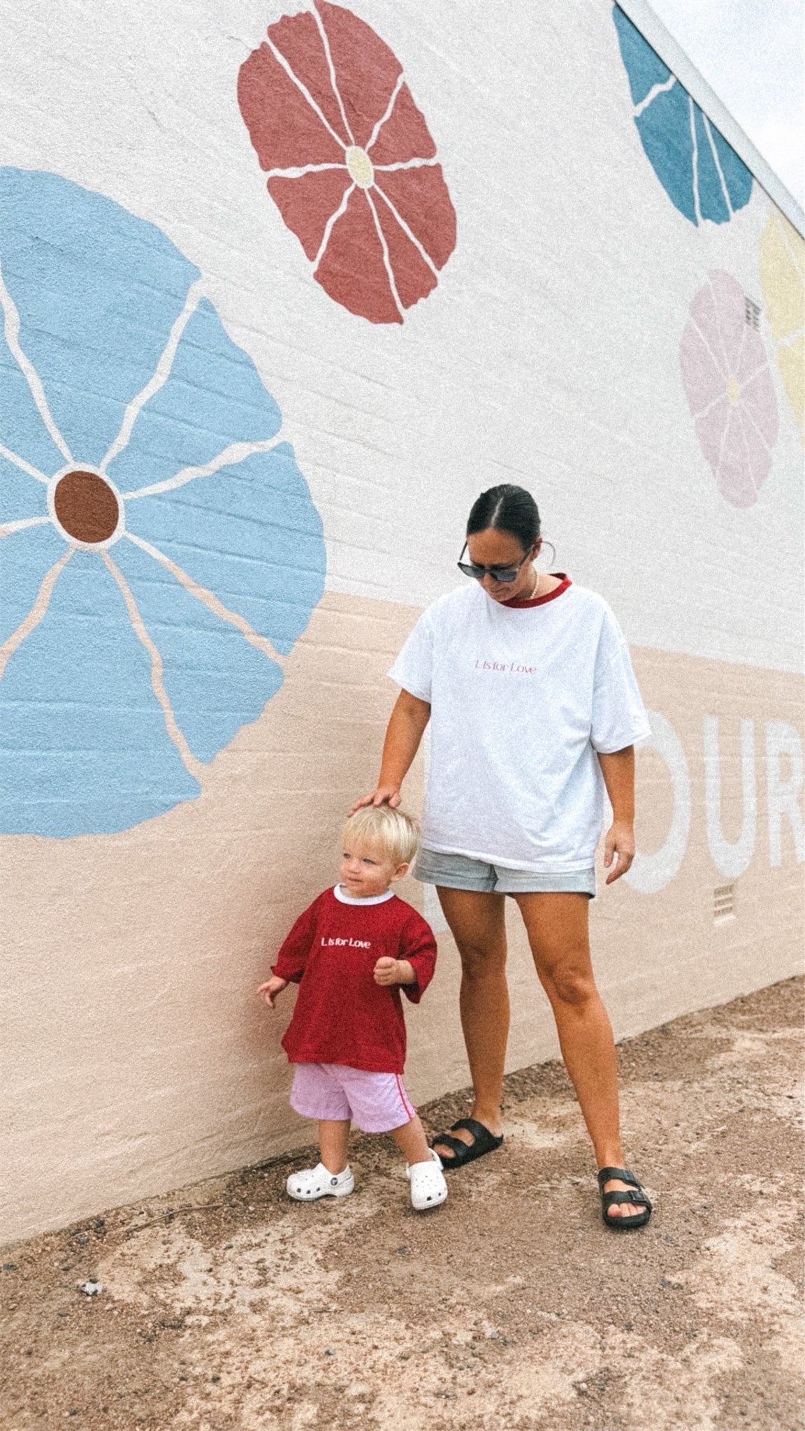 Woman and child standing in front of a colorful mural.