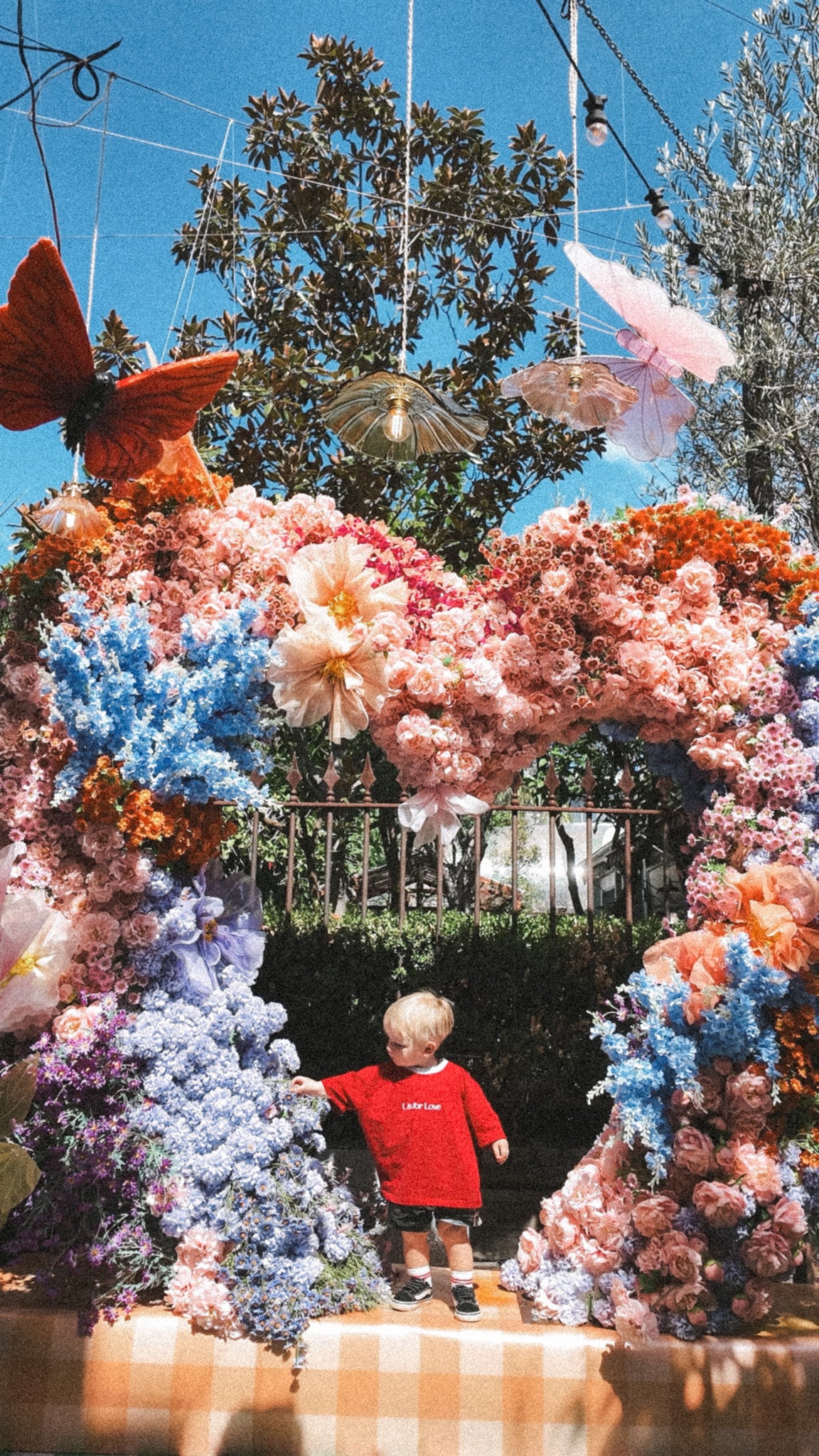 Colorful floral archway with a child in a red shirt standing underneath.