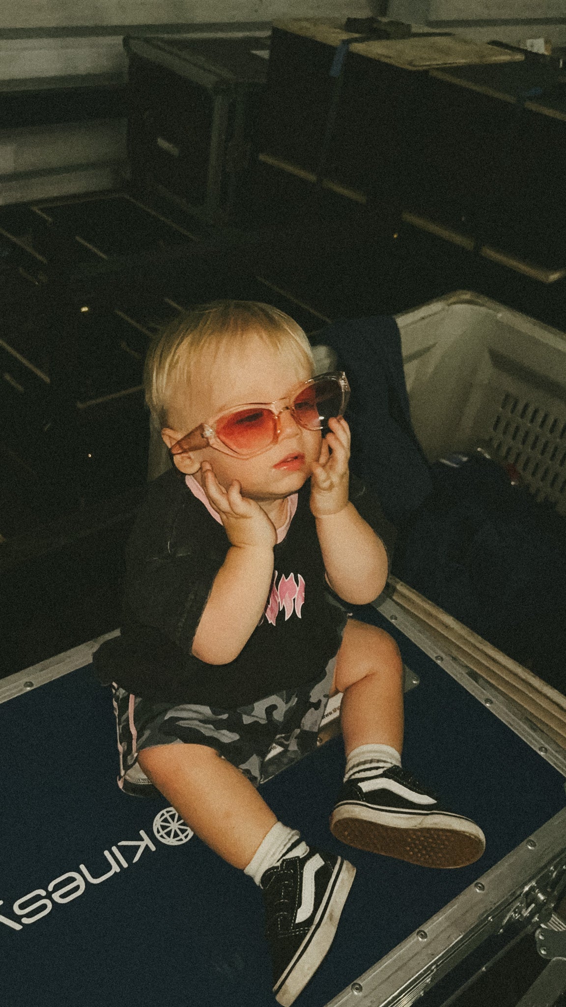 Child sitting in a suitcase wearing pink sunglasses