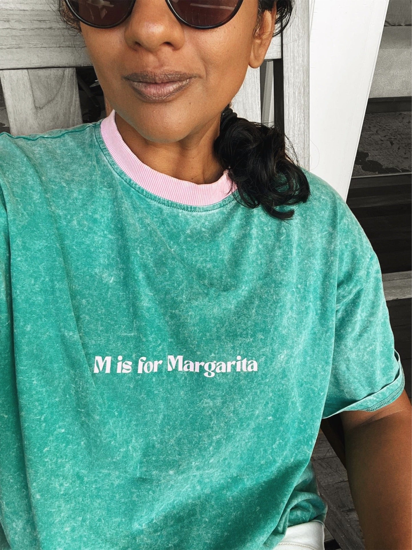 Person wearing a teal t-shirt with 'M is for Margarita' text.