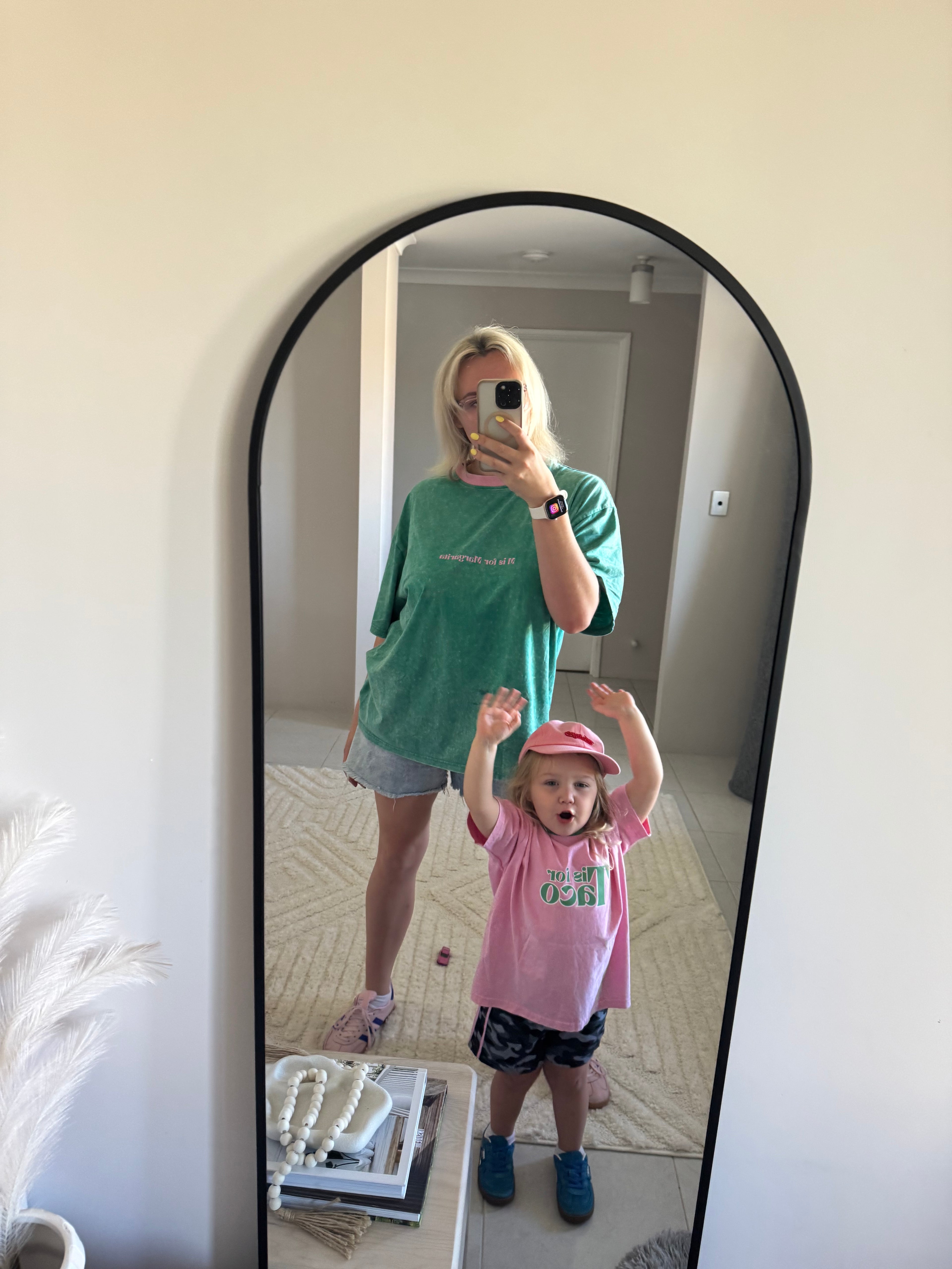 Two people standing in front of a mirror, reflected view.