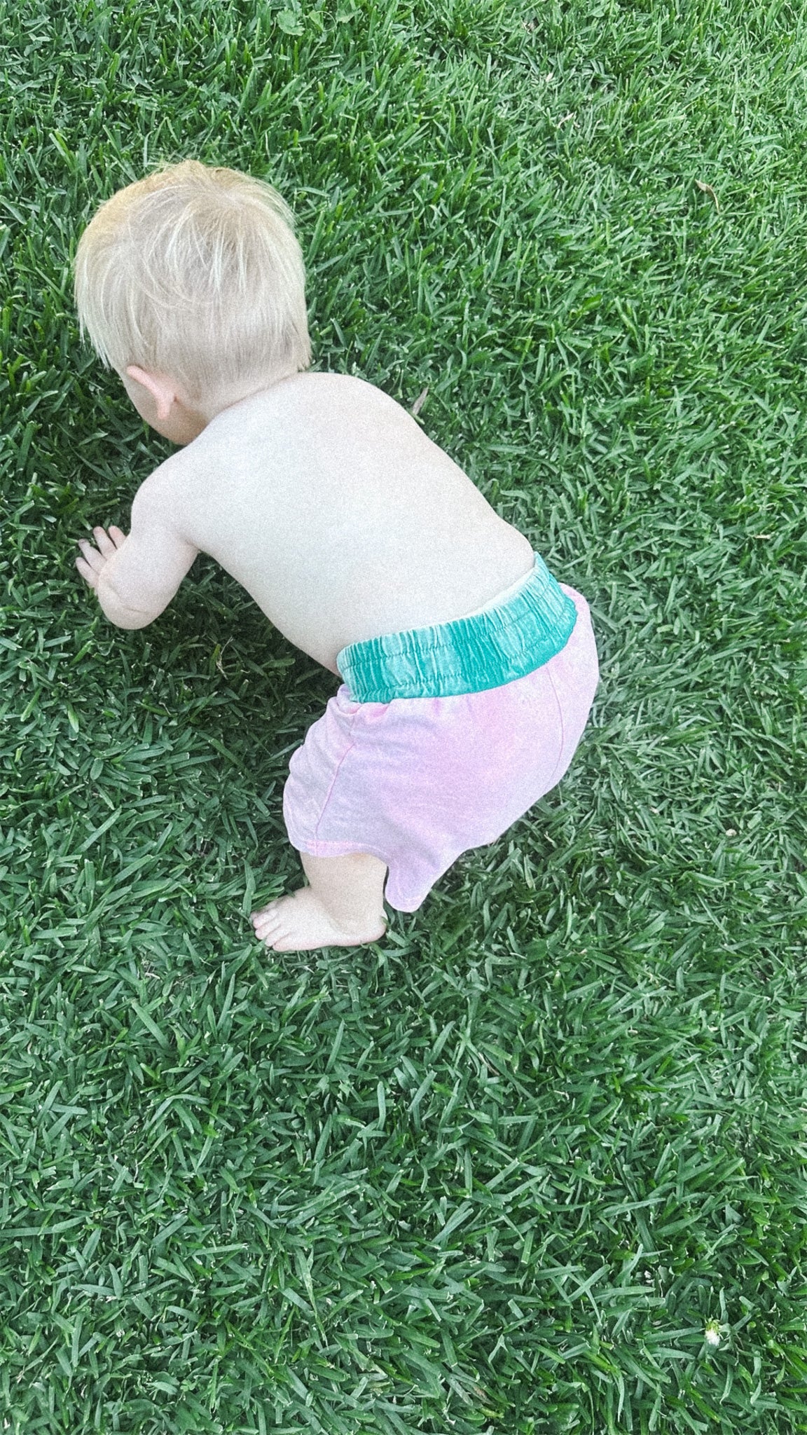 toddler in pink and green acid wash shorts on grass