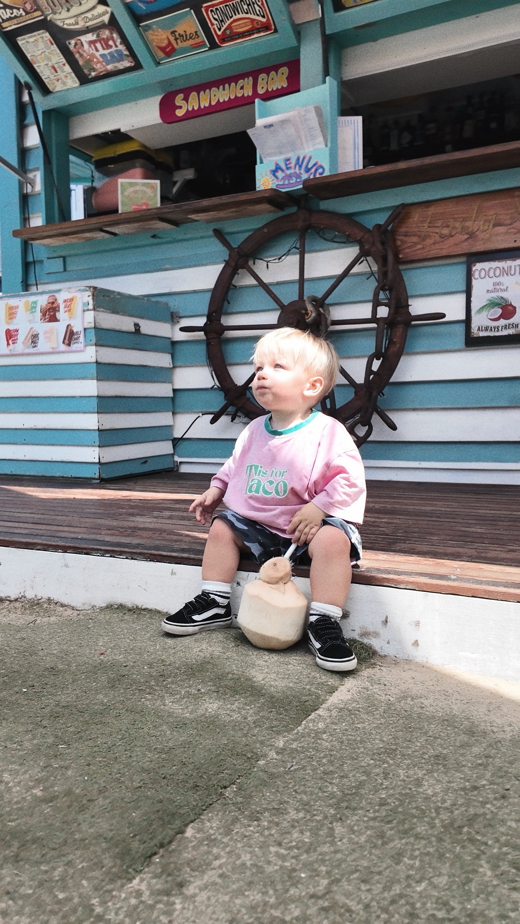 Child sitting on a bench drinking coconut